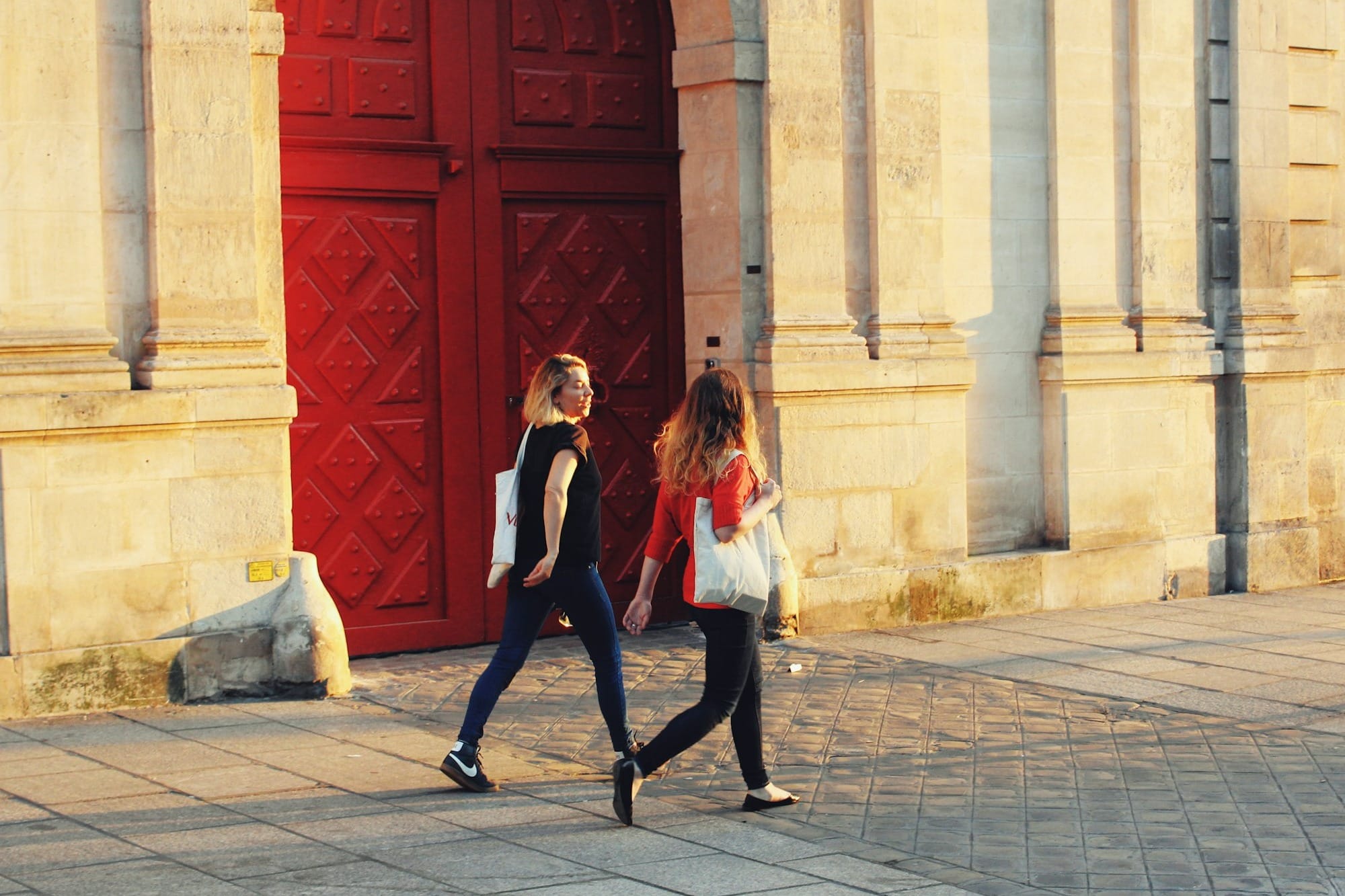 two women walking near red door